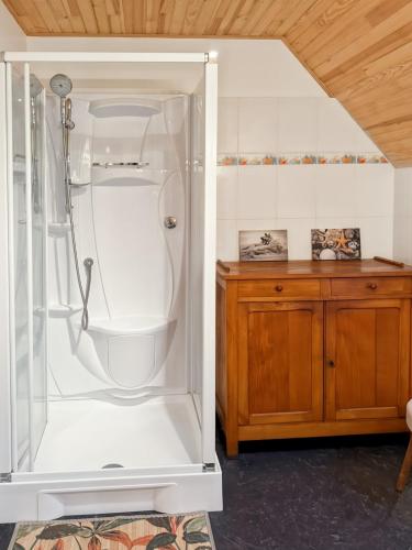 La salle de bains est pourvue d'une douche blanche et d'une armoire en bois. dans l'établissement Le refuge de la vallée - 4 à 6 pers - proche de Salers, à Saint-Projet-de-Salers