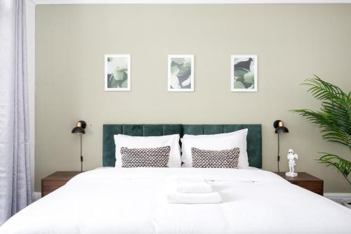 a bedroom with a large white bed with four pictures on the wall at Ocean Breeze in Thorpe Bay