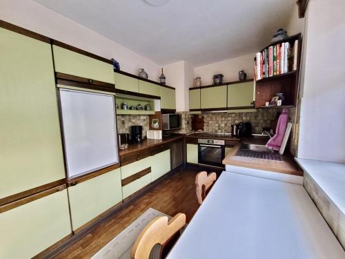 a kitchen with green cabinets and a white table at 10 Min zur Altstadt, Scheunen Ferienwohnung, Sternenhimmel im Wintergarten mit Grill, Lift und Kino in Trier