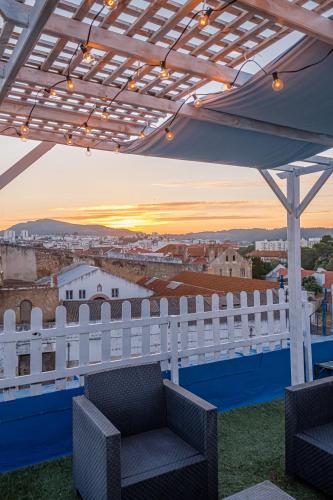 a balcony with a white fence and chairs and a sunset at Y Quebedo - Boutique Apartments in Setúbal