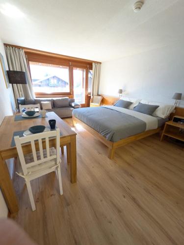 a bedroom with a bed and a table and a couch at Studio with balcony, Niesen view & free parking near Interlaken, Thunersee & Blausee in Aeschi bei Spiez