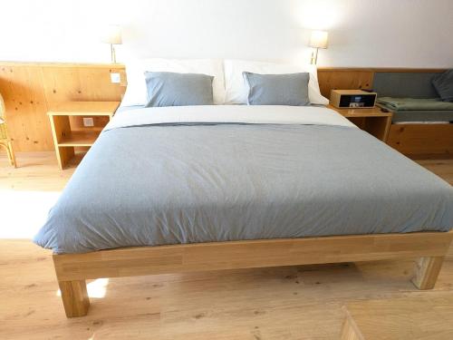 a large bed with blue pillows in a bedroom at Studio with balcony, Niesen view & free parking near Interlaken, Thunersee & Blausee in Aeschi bei Spiez