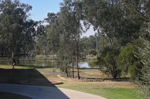 a person standing next to a pond in a park at Forbes Victoria Inn in Forbes