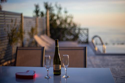 a bottle of wine sitting on a table with two glasses at Villa Aurora Azure - Luxury Infinity Pool Resort in Katun