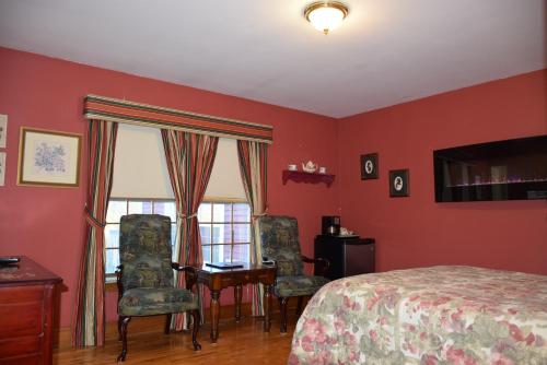 a bedroom with a bed and a desk and chairs at Auberge Wild Rose Inn in Moncton