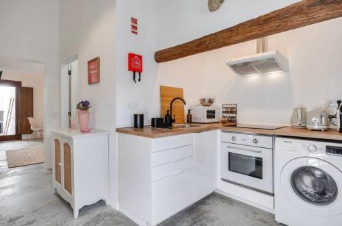 a white kitchen with a washer and dryer in it at Casa Do Largo-Alqueva in Campinho