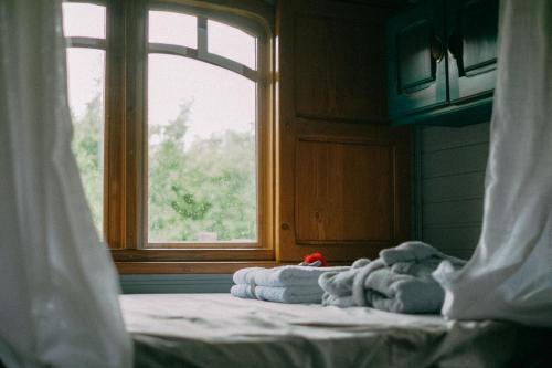 une pile de serviettes assises sur un lit devant une fenêtre dans l'établissement Echolotte la roulotte, à Bernex