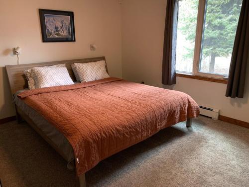 a bedroom with a bed with an orange blanket and a window at Two Bedroom in Great Location in Fairbanks
