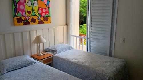 two twin beds in a room with a window at Exclusiva Casa 18G em Juqueí em Condomínio Resort de Luxo in Juquei