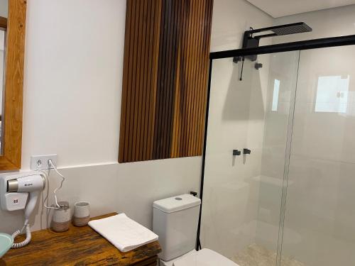 een badkamer met toilet en glazen douche bij Maluhia Ilhabela 1 in Ilhabela
