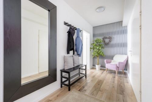 a mirror in a hallway with a pink chair at Deluxe Appartements am Münster in Freiburg im Breisgau
