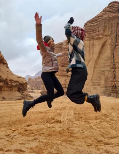 two people jumping in the air in the desert at Rum gate camp Fares in Disah