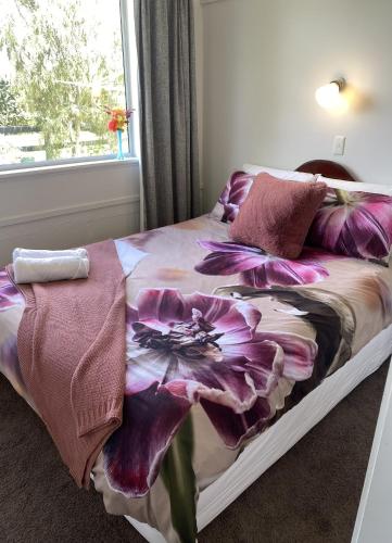 a bed with a purple flower blanket on it at Horseinaround in Cambridge