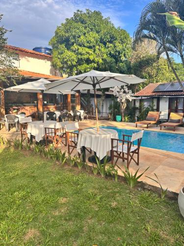 a patio with tables and umbrellas next to a pool at Casa Valldemossa in Búzios