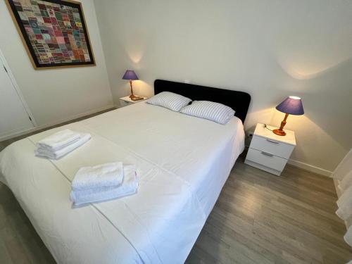 Un dormitorio con una cama blanca con toallas. en Santiago Apartment, en Caminha