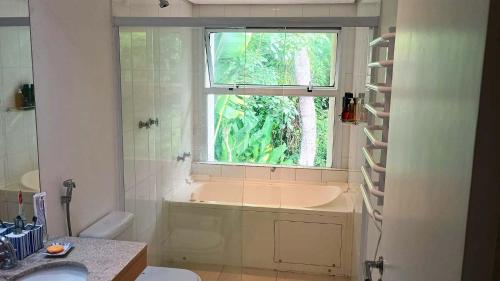 a bathroom with a bath tub and a window at Exclusiva Casa 18G em Juqueí em Condomínio Resort de Luxo in Juquei
