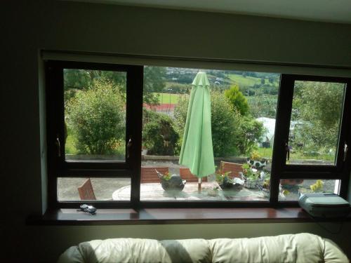 a window view of a patio with a green umbrella at Artisthostel Letterkenny in Letterkenny