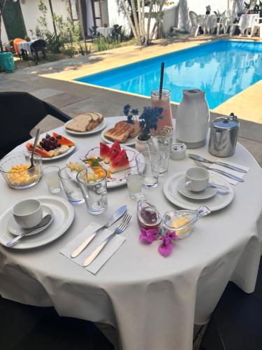 a white table with food on it next to a pool at Casa Valldemossa in Búzios