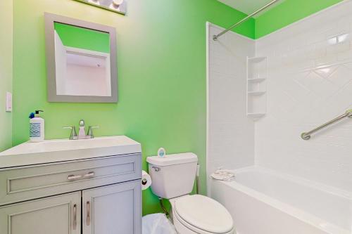 a bathroom with a white toilet and a green wall at Rainbow Cove --- 117 Dagsworthy Ave #B in Dewey Beach