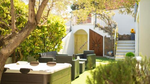 a patio with chairs and a table in a yard at Veranda with Jacuzzi & BBQ 1 minute from the Beach in Capo Comino