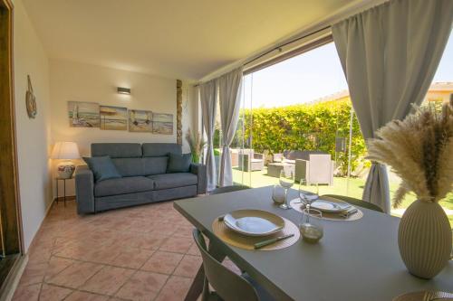 a living room with a table and a couch at Veranda with Jacuzzi & BBQ 1 minute from the Beach in Capo Comino