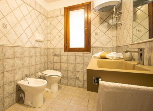 a bathroom with a toilet and a sink at Veranda with Jacuzzi & BBQ 1 minute from the Beach in Capo Comino