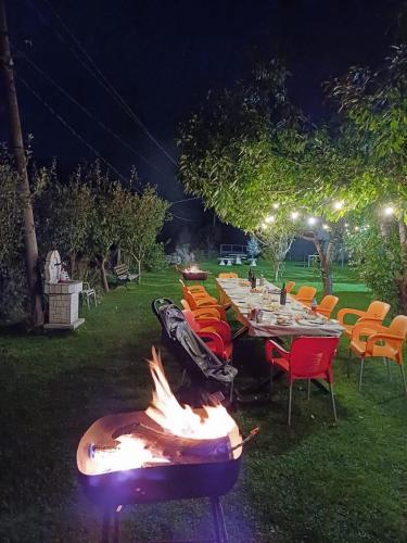 a long table with chairs and a fire pit at night at Villa Tomorrow in Ujanik