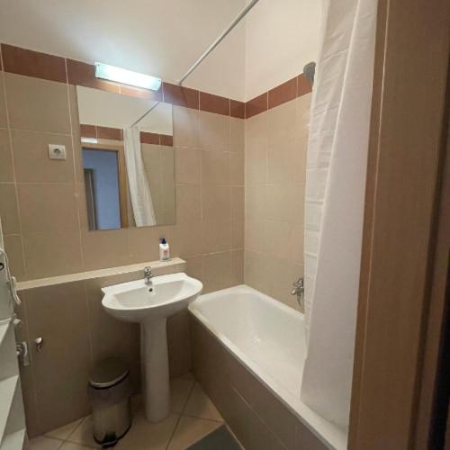 a bathroom with a sink and a tub and a mirror at Klikk Apartments at Gozsdu in Budapest