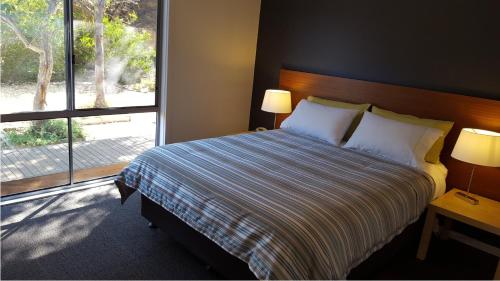 a bedroom with a bed with two lamps and a window at Coorong Waterfront Retreat in Meningie