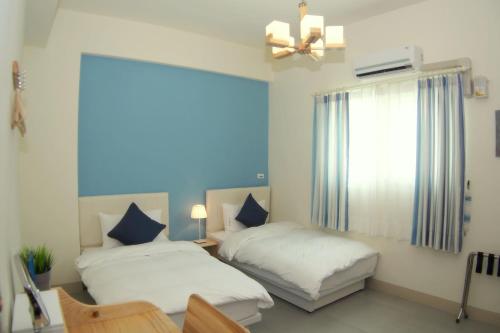 a bedroom with two beds and a desk and a window at Heye Homestay in Ruisui
