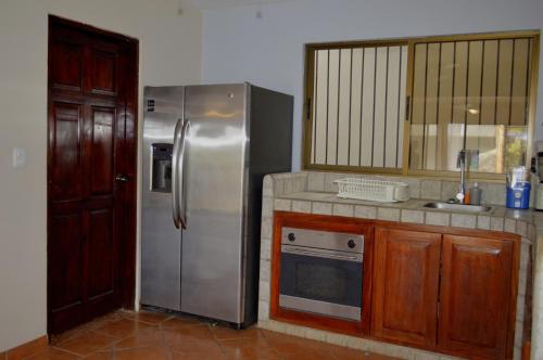a kitchen with a stainless steel refrigerator and wooden cabinets at Apartotel VILLA ALTA TAMARINDO in Tamarindo
