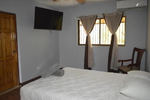 a bedroom with a bed and a flat screen tv at Apartotel VILLA ALTA TAMARINDO in Tamarindo