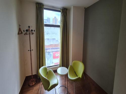 a room with two green chairs and a window at Hotel O Crossroads Hotel in Kuala Lumpur