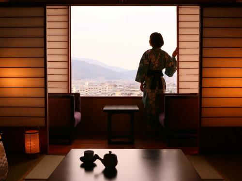 a woman looking out the window of a room at Hotel Tamanoyu in Matsumoto