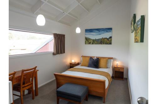 a bedroom with a bed and a desk and a window at Tawa Retreat - Wellington Holiday Home in Wellington