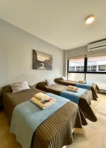 a room with three beds with towels on them at Av Suites in Rosario