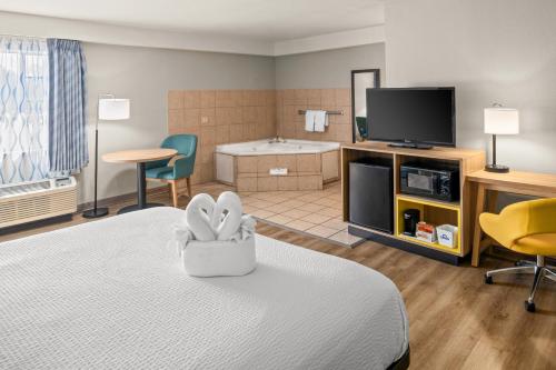 a hotel room with a bed and a television at Days Inn & Suites by Wyndham Artesia in Artesia
