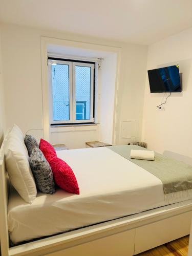 a bedroom with a large white bed with red pillows at Travessa do Meio Apartment in Lisbon