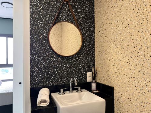 a bathroom with a sink and a mirror on a wall at NOVO - Studio aconchegante no Campo Belo in Sao Paulo