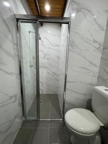 a bathroom with a toilet and a glass shower at Bunkhouse Motel Cooma in Cooma