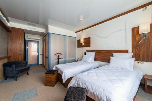 a hotel room with two beds and a chair at Inn OZZ in Karagandy
