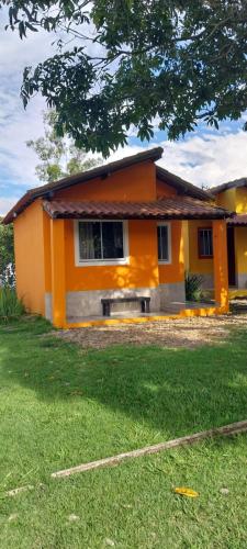 a small orange house with a lawn in front of it at Sitio148 Hospedaria in Penedo