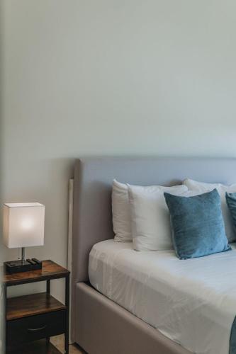 a bed with blue and white pillows and a lamp at Depto de Lujo frente al Mar in San Bruno