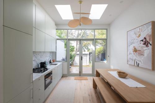 a kitchen with white cabinets and a wooden table at Exquisite Modern 3 Bed Home in Newtown w Parking in Sydney