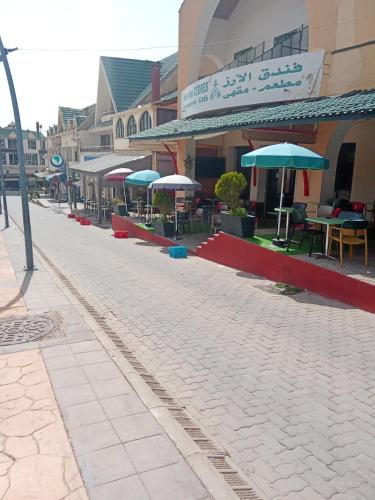 a street with tables and umbrellas in front of a building at Hôtel des cèdres azrou province ifrane in Azrou