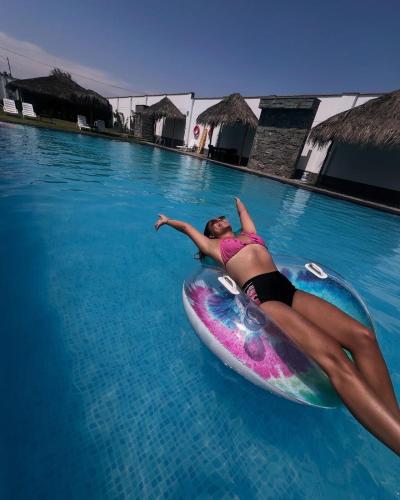 a woman laying on a surfboard in the water at Hotel Kendari - Chincha in Chincha