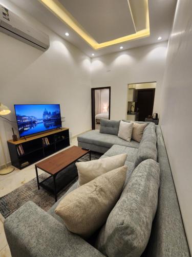 a living room with a couch and a tv at نجدية - كافد وبوليفارد الرياض in Riyadh