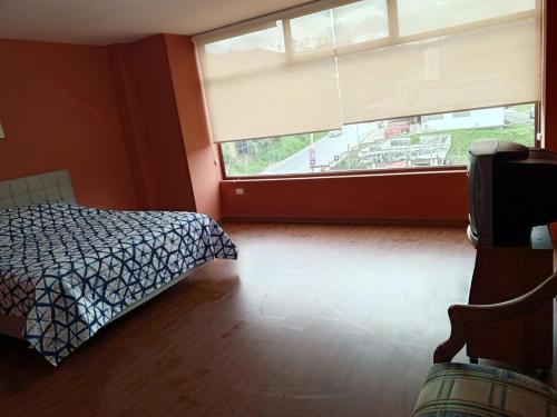 a bedroom with a bed and a large window at Hostal Casa Alamos in Guaranda