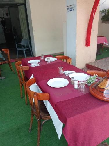 a table with a purple table cloth and plates on it at Hôtel des cèdres azrou province ifrane in Azrou