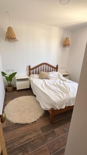 a bedroom with a bed with white sheets and a rug at Casa Ancona casa quinta in Joaquín Gorina